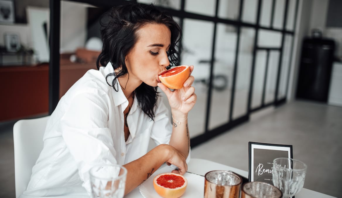close up of woman eating grapefruit at home
