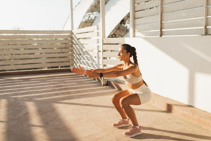 woman doing squats, interval endurance workout outdoors. effort and concentration. female power