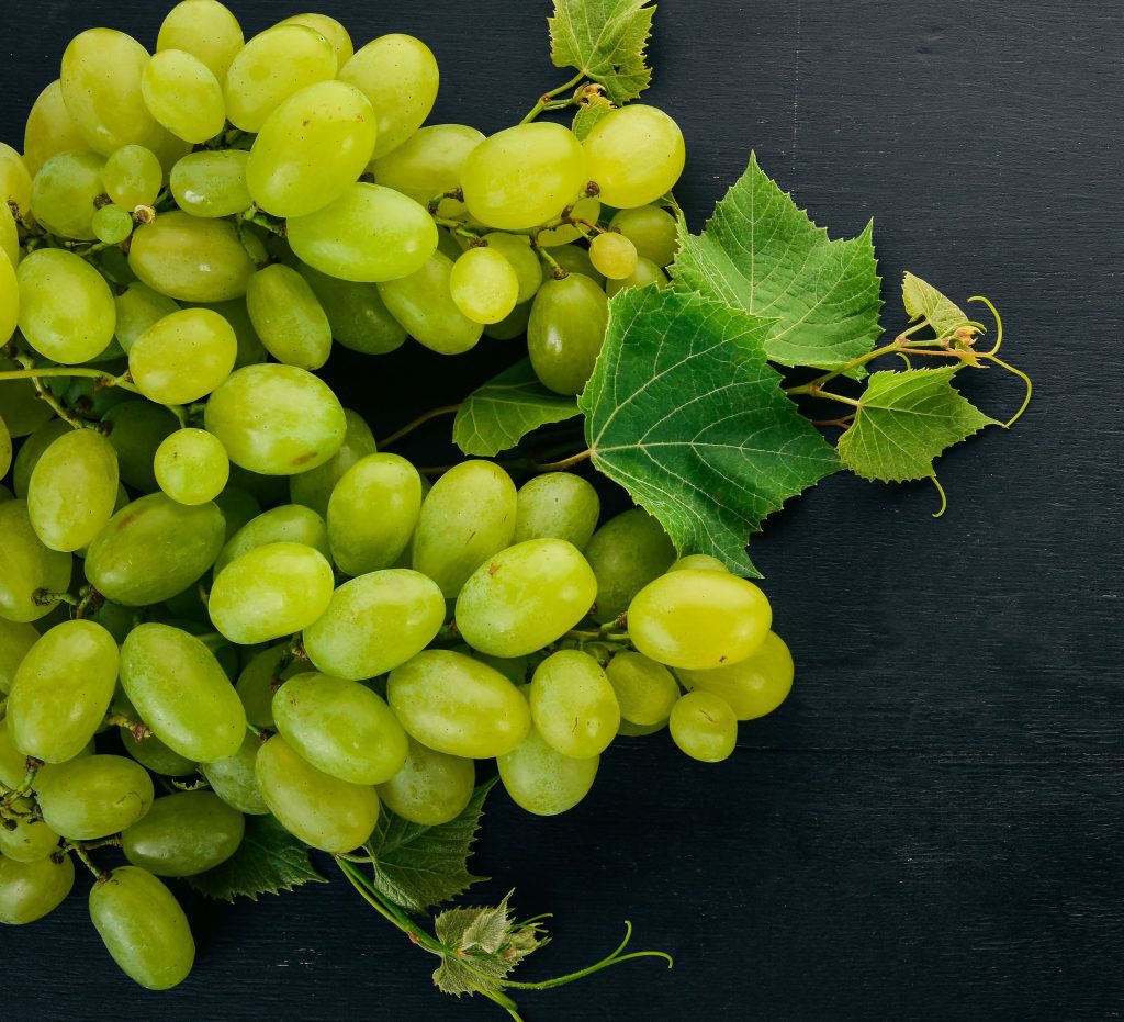 fresh green grapes with leaves of grapes. top view. on a black w