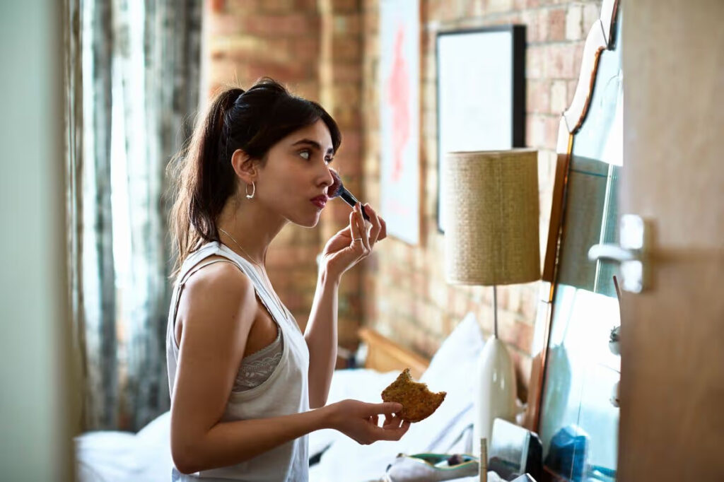 2 young woman applying blusher with make up and holding toast